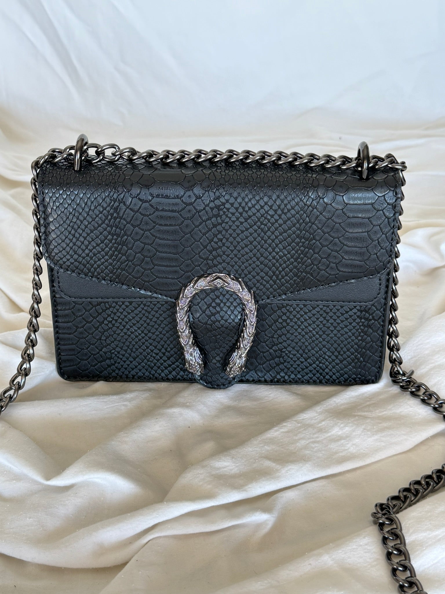 Statement τσάντα με snake-effect υφή και μεταλλική λεπτομέρεια που τραβάει τα βλέμματα.