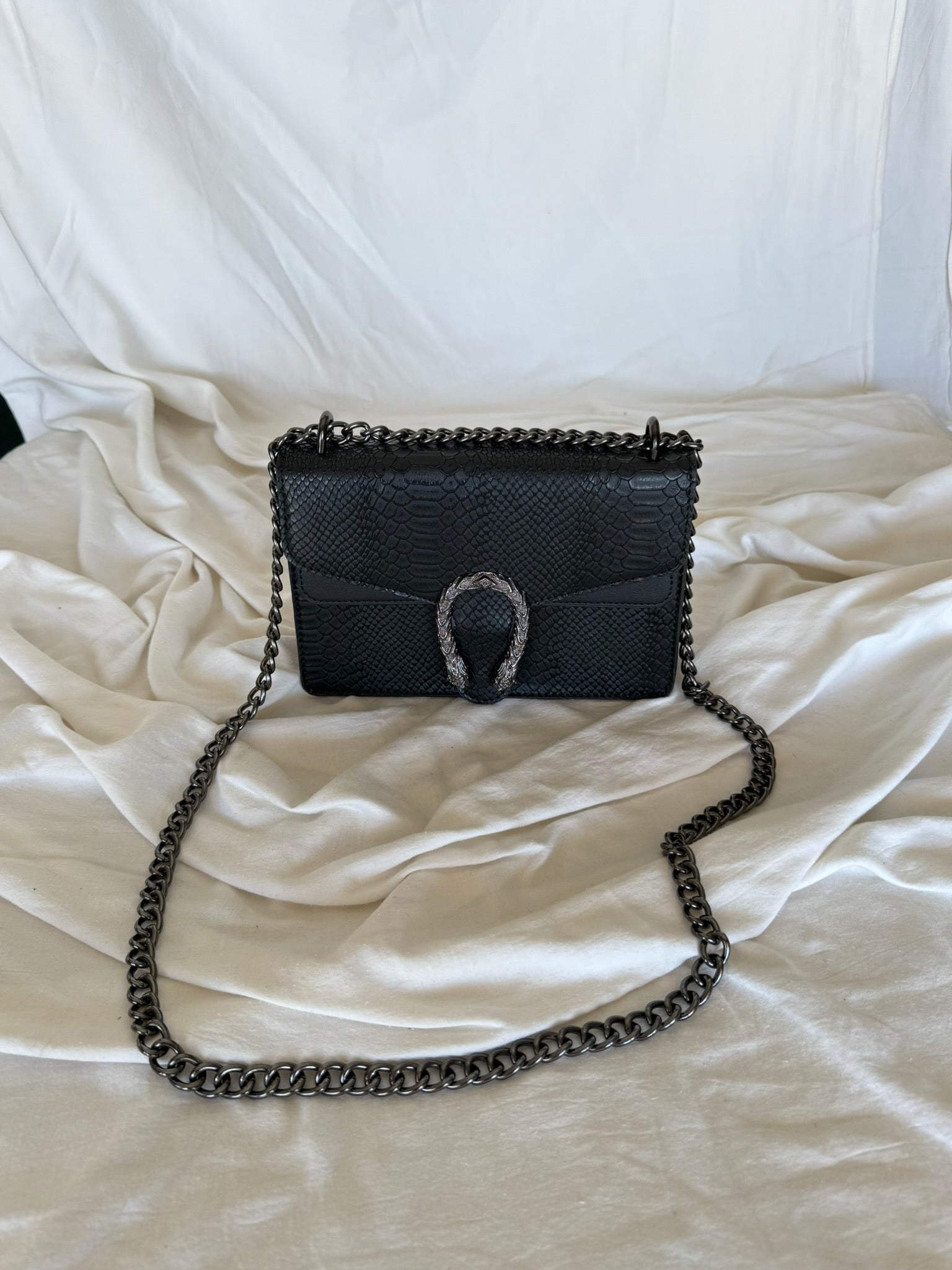 Statement τσάντα με snake-effect υφή και μεταλλική λεπτομέρεια που τραβάει τα βλέμματα.