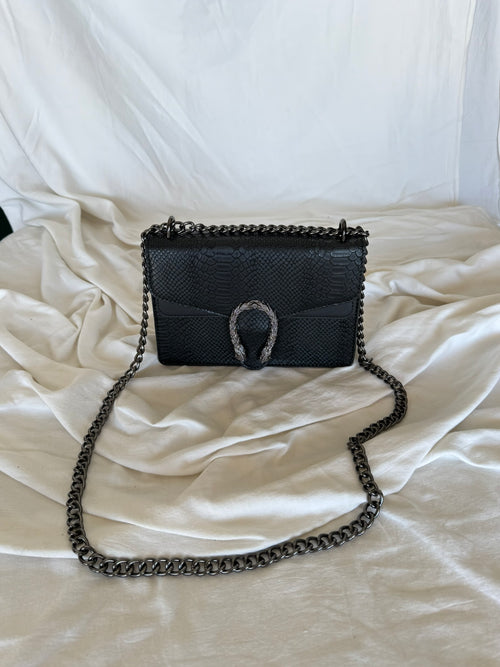 Statement τσάντα με snake-effect υφή και μεταλλική λεπτομέρεια που τραβάει τα βλέμματα.