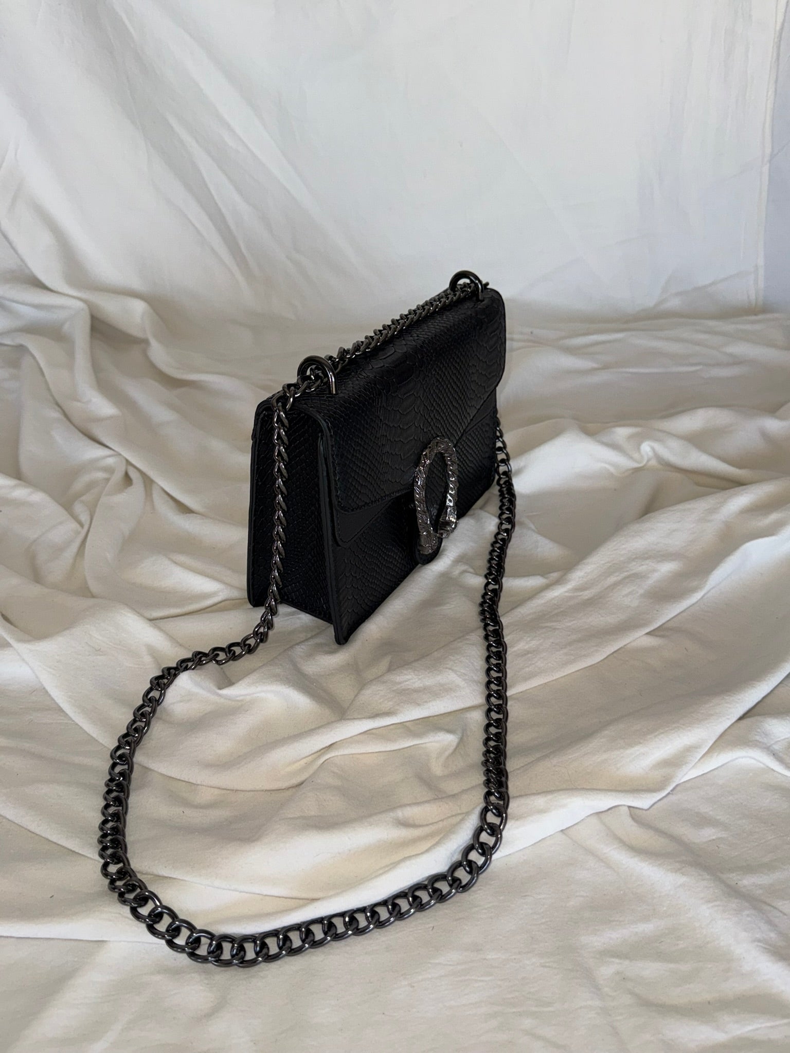 Statement τσάντα με snake-effect υφή και μεταλλική λεπτομέρεια που τραβάει τα βλέμματα.