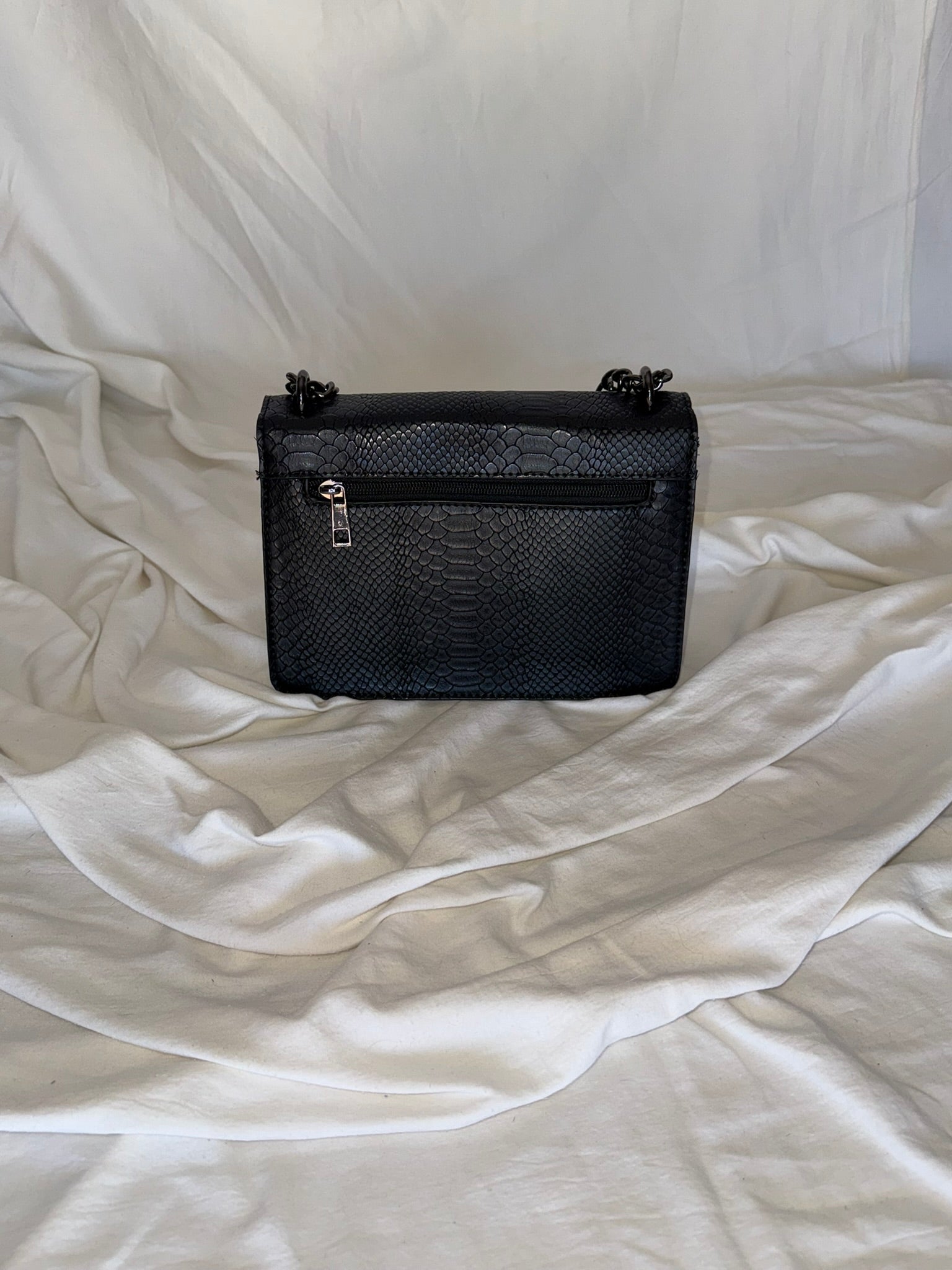 Statement τσάντα με snake-effect υφή και μεταλλική λεπτομέρεια που τραβάει τα βλέμματα.